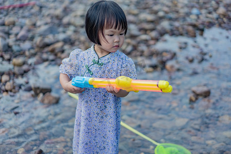 小孩玩水摄影照片_玩水女孩夕阳女孩阳朔玩水枪摄影图配图