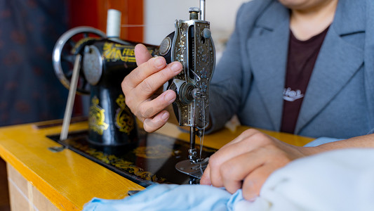 70年代穿衣摄影照片_缝制衣服八十年代裁缝师室内做衣服摄影图配图