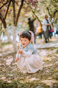 春游汉服儿童白天可爱小女孩户外公园蹲着玩耍摄影图配图