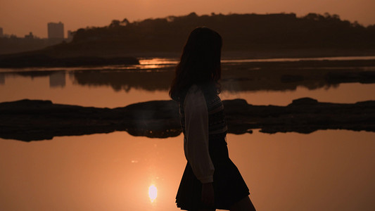 美女剪影摄影照片_夕阳下女孩江边行走剪影唯美