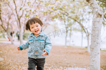 儿童节快乐摄影照片_儿童春游白天小女孩户外公园歪头奔跑摄影图配图