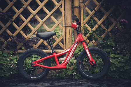 花园红色儿童自行车下午儿童自行车室外摄影摄影图配图