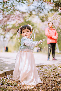 转圈字体摄影照片_儿童白天可爱小女孩户外樱花树转圈圈摄影图配图