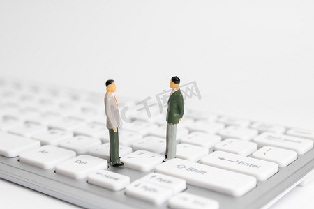 商务办公棚拍两个微距小人在键盘上站着摄影图配图