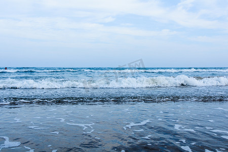 青岛海边摄影照片_青岛白天海浪沙滩涨潮摄影图配图