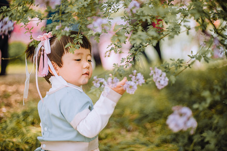 儿童节摄影照片_春游汉服儿童白天可爱小女孩户外公园丁香花闻花香摄影图配图