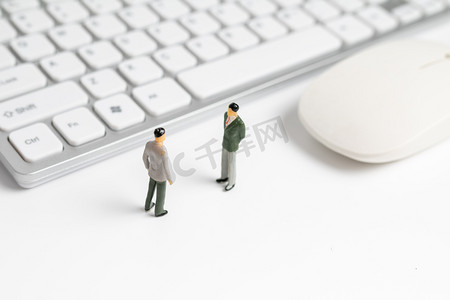办公小人摄影照片_商务办公室内两个微距小人键盘鼠标附近站着摄影图配图