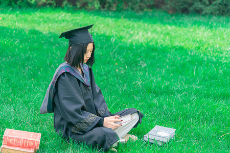 毕业学士服摄影照片_毕业白天学士服女生读书户外读书摄影图配图