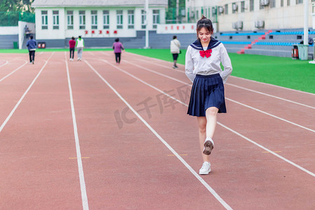 人物白天日系少女操场上踢腿摄影图配图