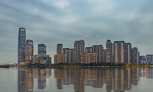 写字楼夜景摄影照片_广州琶洲CBD傍晚建筑群湖面长曝光摄影图配图