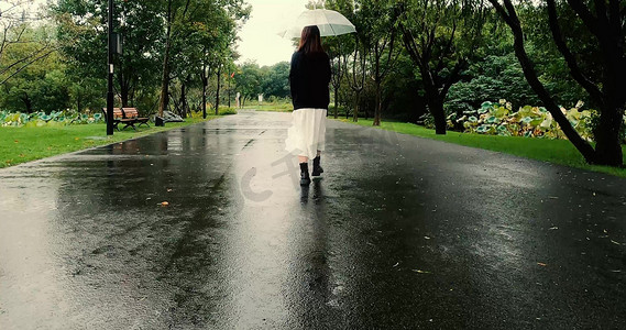 女孩下雨天走在公路上的背影实拍