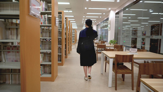 实拍图书馆里到处行走找书籍的女孩背影