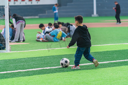 足球联赛展板摄影照片_儿童节白天男孩足球体育场踢球摄影图配图