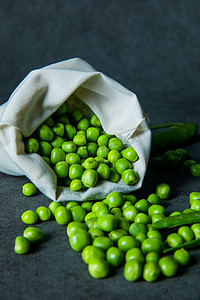 美食摄影照片_蔬菜豆类白天装在袋子里撒出来的豌豆室内摆拍摄影图配图