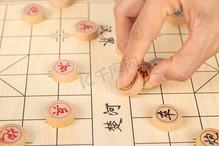 古人博弈摄影照片_中国象棋白天手执棋子棋牌室下棋摄影图配图