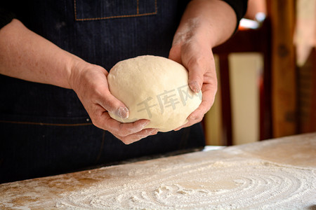 面粉做饭摄影照片_美食白天手中的面团室内拿着摄影图配图