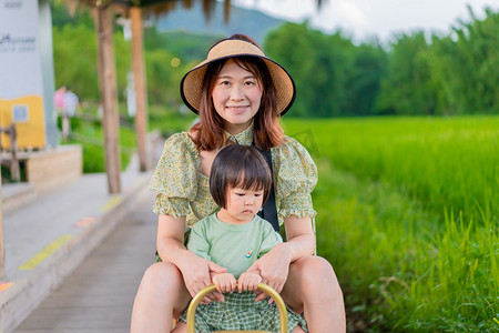 克蓝英蓝笑脸摄影照片_坐小火车的母女夏季傍晚母女户外正面摄影图配图