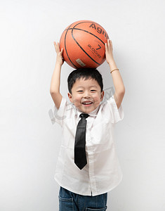 运动男孩摄影照片_六一儿童节白天男孩室内头顶篮球摄影图配图