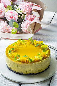 慕斯蛋糕蛋糕摄影照片_芒果慕斯蛋糕和花束中午芒果慕斯蛋糕花束室内静物摄影图配图