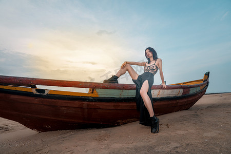 杂志风摄影照片_海岛旅行傍晚穿比基尼的女孩户外海滩坐木船上摄影图配图