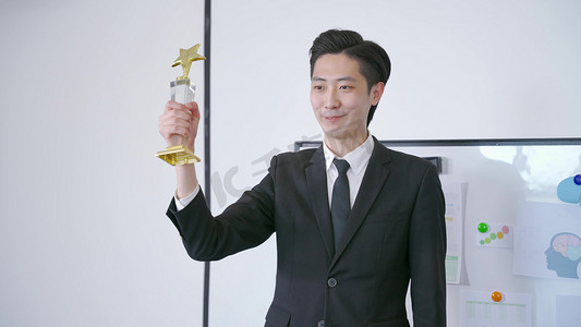 精英商务人士摄影照片_青年男性职员白领获奖杯炫耀