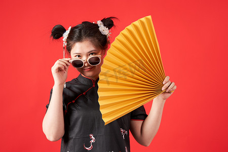 新中国风摄影照片_国潮传统文化女孩一手拿着折扇一手扶着墨镜摄影图配图