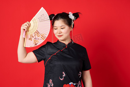 国潮中国风红色摄影照片_国潮红色背景女子拿着折扇放在侧脸摄影图配图