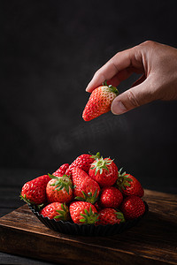 美食四季一盘草莓室内手拿起一个草莓摄影图配图