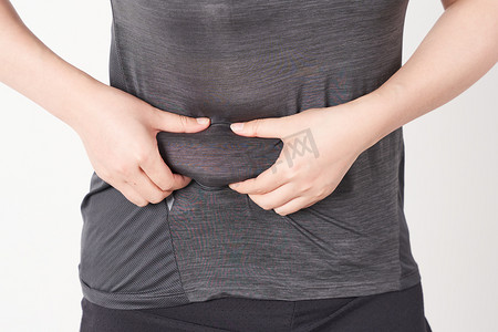 减肥肥胖女孩手捏出腰上的肥肉摄影图配图