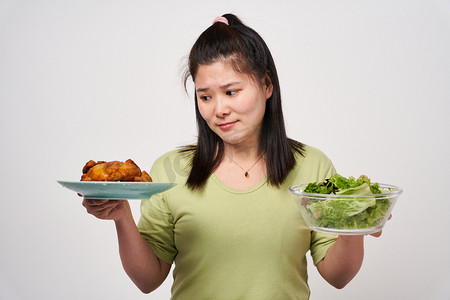 选择摄影照片_肥胖选择女生健康饮食和烤鸡犹豫不决摄影图配图