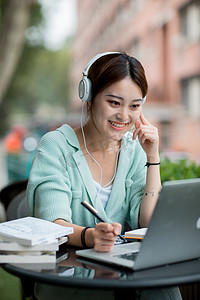 正在考试的人摄影照片_教育白天正在上网课的女孩户外微笑摄影图配图