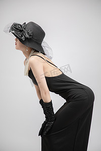 黑色大气时尚摄影照片_复古赫本风白天美女室内弯腰摄影图配图