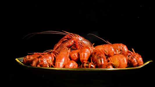 夏日美食背景摄影照片_黑色背景上一盘旋转的小龙虾