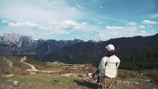 坐在山顶摄影照片_女生坐在山顶欣赏自然风景背影