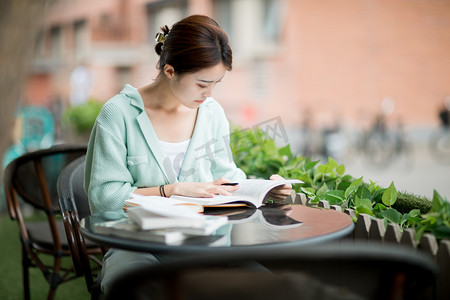 学生看书摄影照片_教育考研白天一个女学生户外低头看书摄影图配图