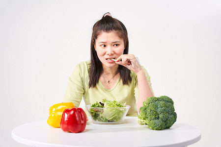 瘦身摄影照片_减肥瘦身女孩嫌弃的吃着蔬菜沙拉摄影图配图
