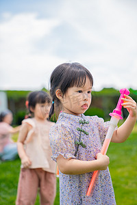 幼儿园娃娃摄影照片_玩泡泡的女孩中午儿童户外草地半身照摄影图配图