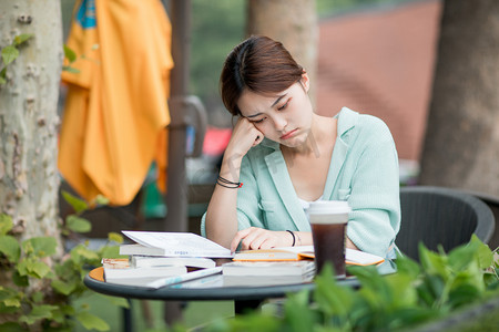 高考备战摄影照片_教育白天思考的女学生户外咖啡厅托下巴摄影图配图