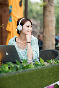 备战台风摄影照片_教育学习白天戴着耳机的女学生户外托下巴望向远方摄影图配图