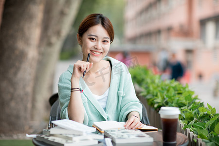 教育学习白天看书学习的女同学户外微笑摄影图配图