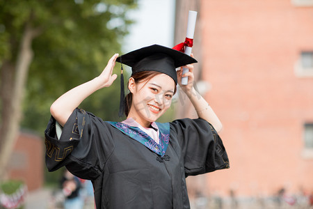 毕业摄影照片_毕业季白天穿着学士服的女毕业生户外戴学士帽摄影图配图