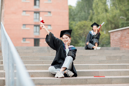 教育白天穿着学士服的美女毕业生户外坐在台阶摄影图配图