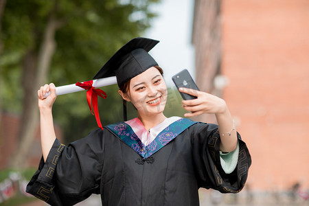 毕业摄影照片_毕业季白天正在视频通话的美女毕业生户外自拍摄影图配图