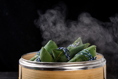 黑色背景摄影照片_美食白天粽子黑色背景冒热气摄影图配图