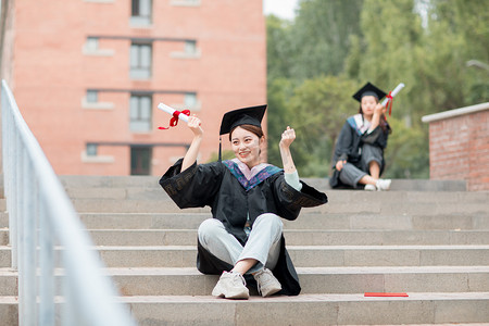 大学毕业照摄影照片_教育白天穿着毕业服的美女毕业生户外加油手势摄影图配图