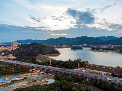 雨后城市摄影照片_城市夕阳水库和高速公路航拍背景摄影图配图