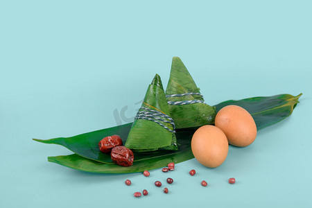 粽子叶粽子摄影照片_美食端午节粽子与鸡蛋蓝色背景摆放摄影图配图