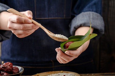 初一初五摄影照片_美食端午节女人家里包粽子摄影图配图