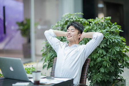 商务白天穿着白衬衫的男青年户外靠在椅子上休息摄影图配图