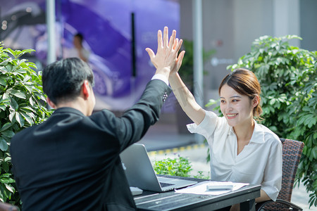 商务合作白天达成一致的商务男女户外击掌摄影图配图